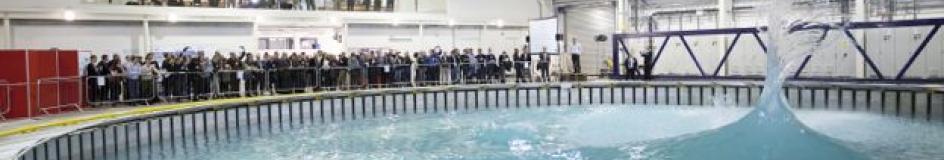View of Flowave wave tank with conical wave formation and many spectators watching on from the side and upper levels